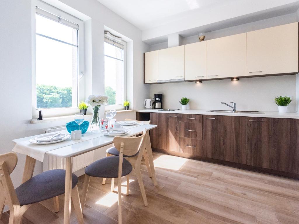 a kitchen with a table and chairs and a kitchen with white cabinets at VacationClub - Aquamarina Apartment C- 21 in Świnoujście