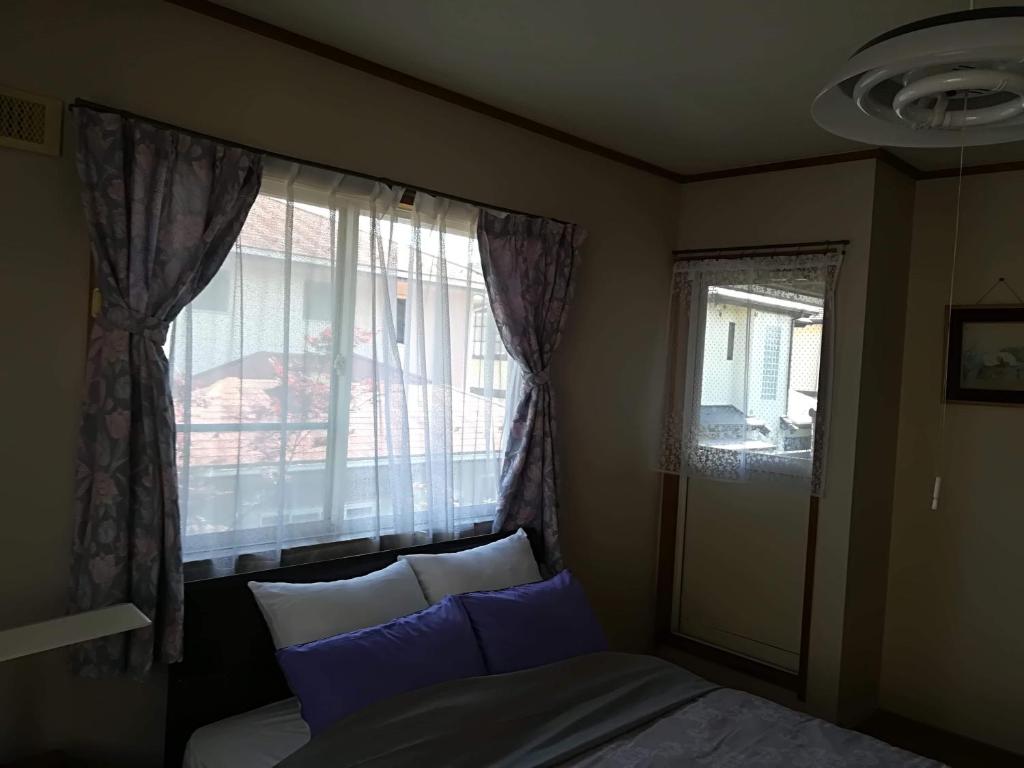 1 dormitorio con cama y ventana con almohadas azules en Jukichi Owada Residence en Sendai