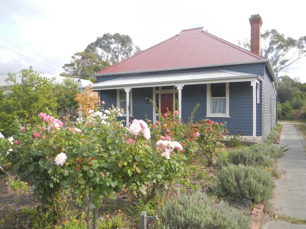 een blauw huis met bloemen ervoor bij Yarram Cottage: Art and Accommodation in Yarram