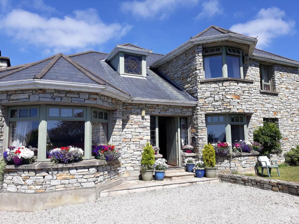 una casa de piedra con flores en el patio delantero en Mill Lane, en Buncrana