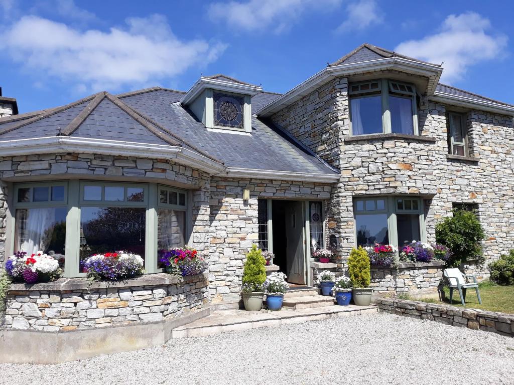 ein Steinhaus mit Blumen im Vorgarten in der Unterkunft Mill Lane in Buncrana