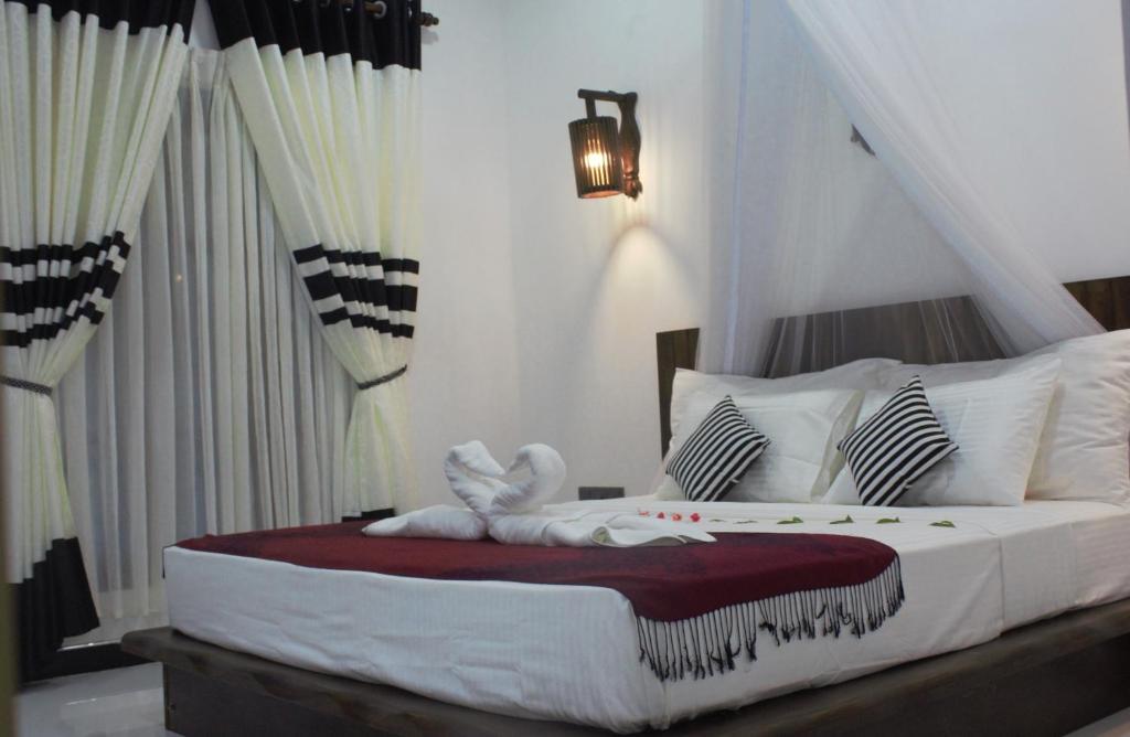 a bedroom with a large white bed with white pillows at Sigiri Veenus Paradise in Sigiriya