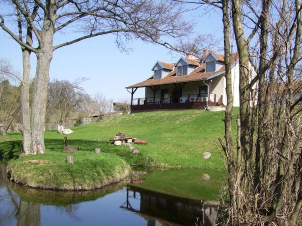 a house sitting on top of a hill next to a river at Chalupa Dejnowo in Pilec