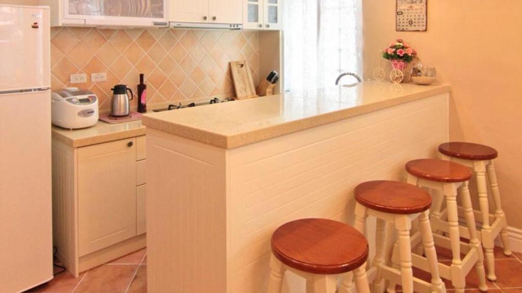 a kitchen with a counter with stools and a refrigerator at Beautiful Life B&amp;B in Dongshan