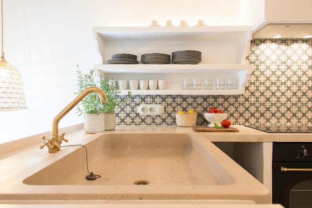 a sink in a kitchen with plates on shelves at Ses Voltes Sant Antoni in Ciutadella