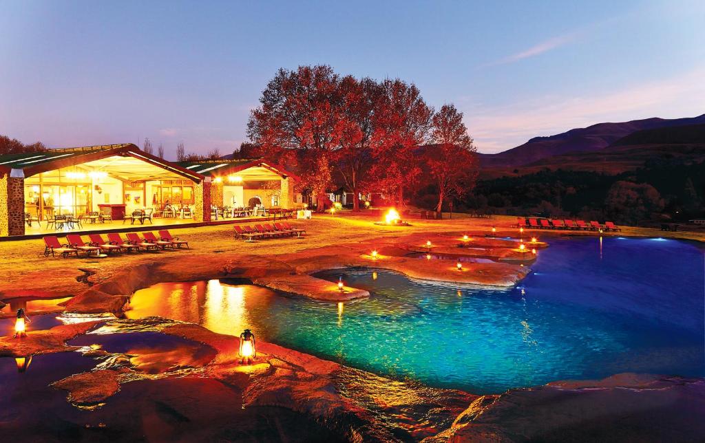 una piscina de agua con luces frente a un edificio en First Group Bushman’s Nek, en Drakensberg Garden