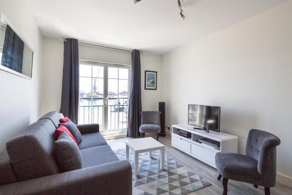 a living room with a couch and a tv at Au Quai Des Pecheurs by Cocoonr in Saint Malo