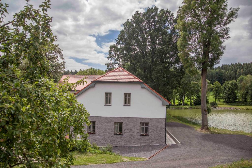 una casa blanca y gris junto a un lago en Jitkovsky mlyn, en Chotěboř