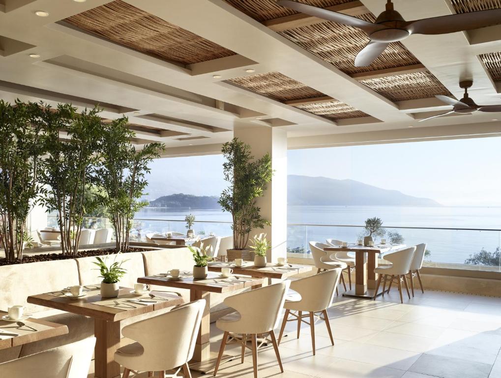 a restaurant with tables and chairs and a view of the ocean at Ikos Dassia in Dassia