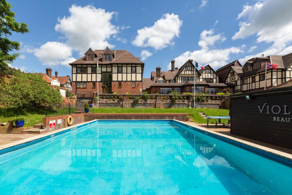 a large swimming pool in front of a house at De Rougemont Manor in Brentwood