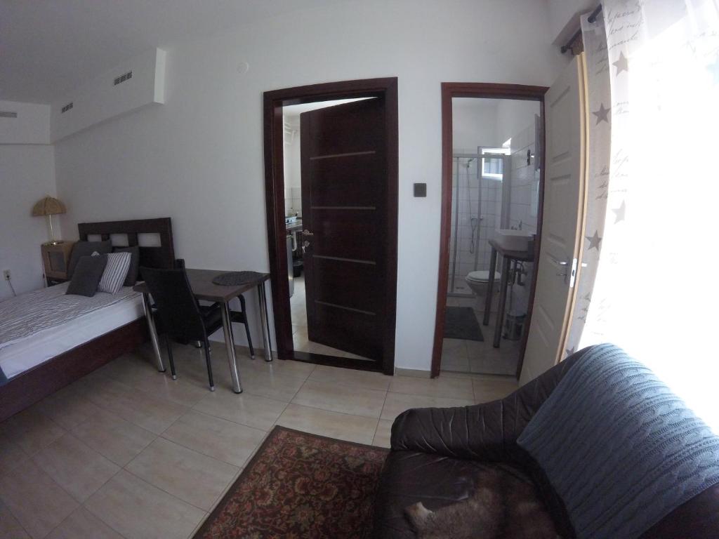 a living room with a bed and a table with a chair at Dózsaház in Zalaegerszeg