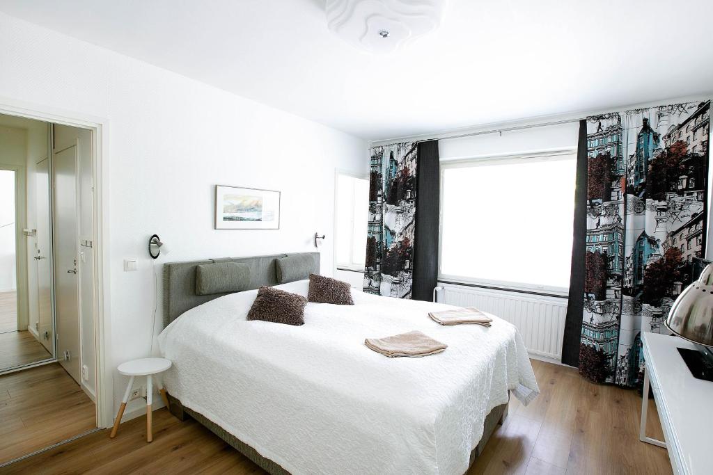 ein weißes Schlafzimmer mit einem Bett und einem Fenster in der Unterkunft Studio Ailos in Naantali