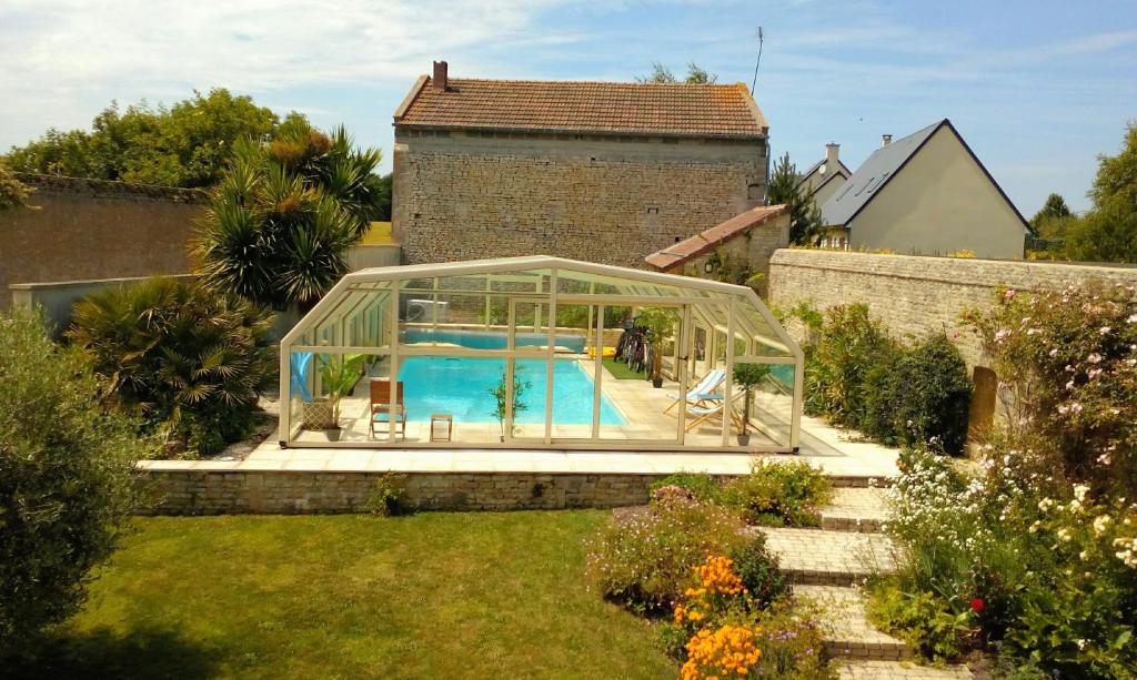 een zwembad in een glazen kas in een tuin bij Villa Athéna,séjour bien-être et éthique in Meuvaines