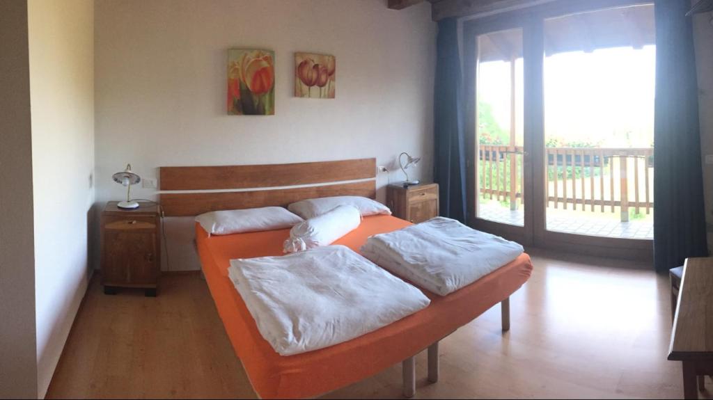 1 dormitorio con cama de color naranja y balcón en Bed & Breakfast Col Mazzet en Belluno