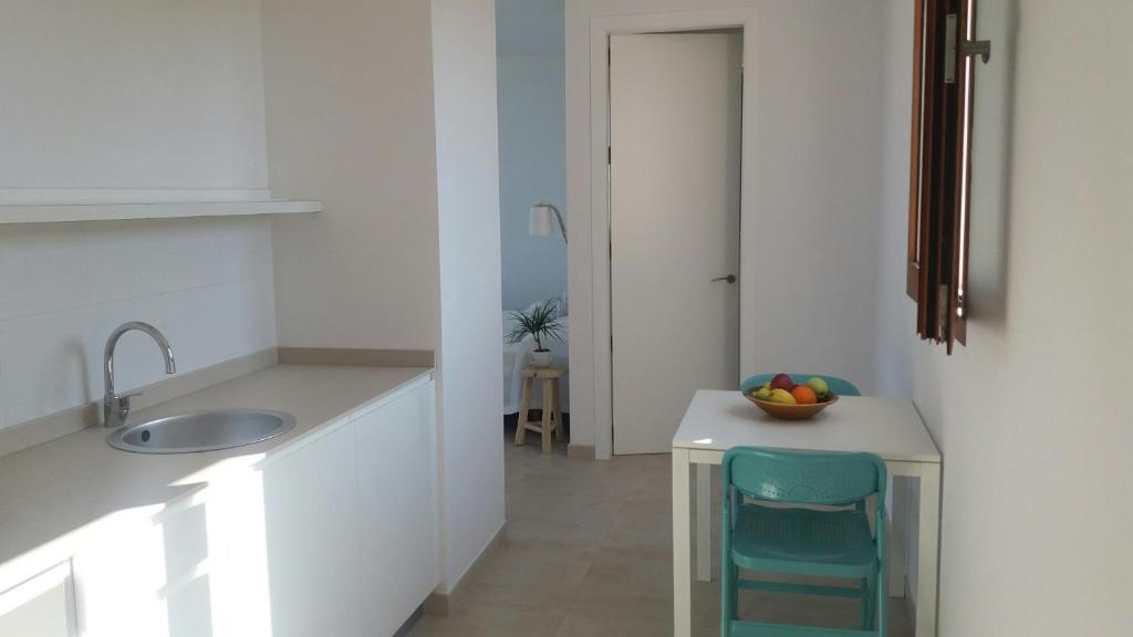 a kitchen with a sink and a table with a chair at Apartamentos Villa Primera in Cala Figuera