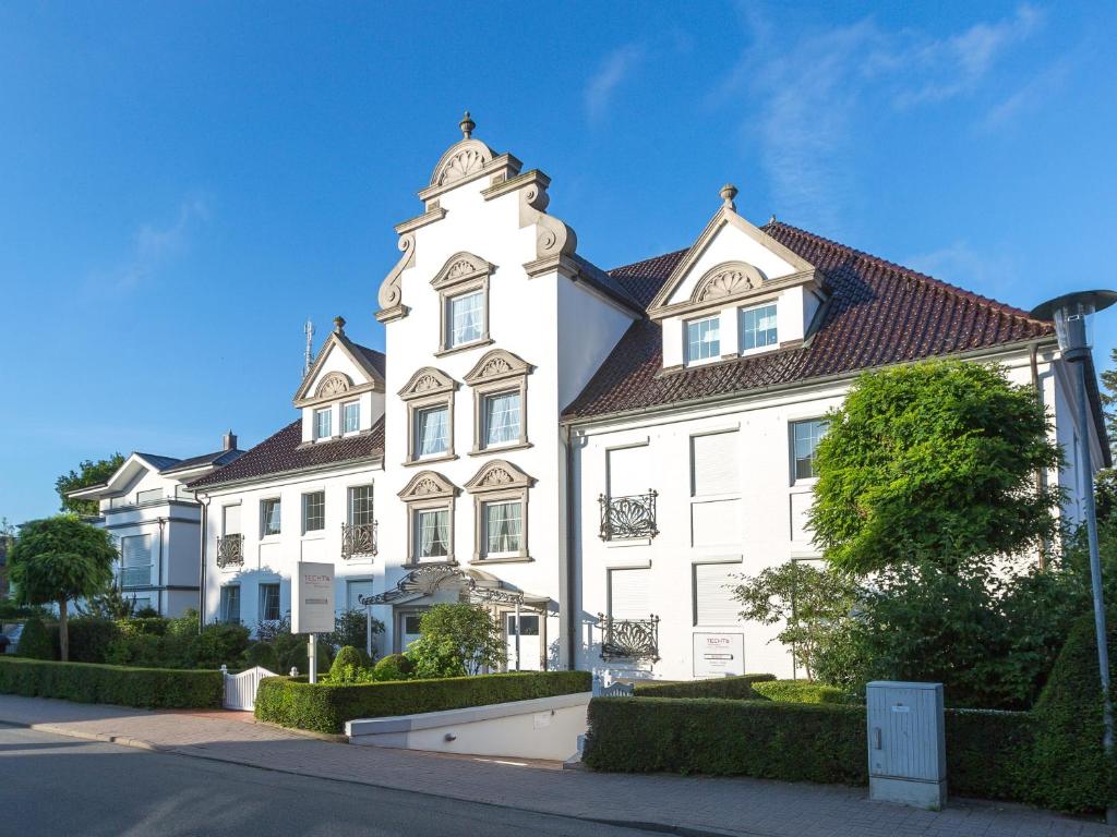 un grande edificio bianco con torre dell'orologio di Techts Apartmenthaus a Timmendorfer Strand