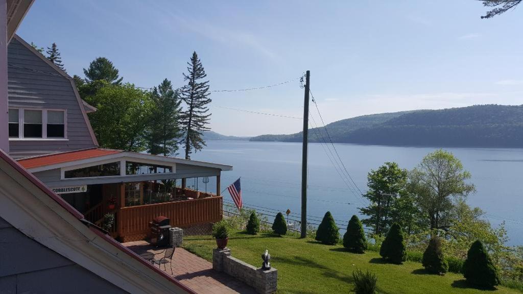 une maison avec vue sur une étendue d'eau dans l'établissement Cobblescote on the Lake, à Cooperstown