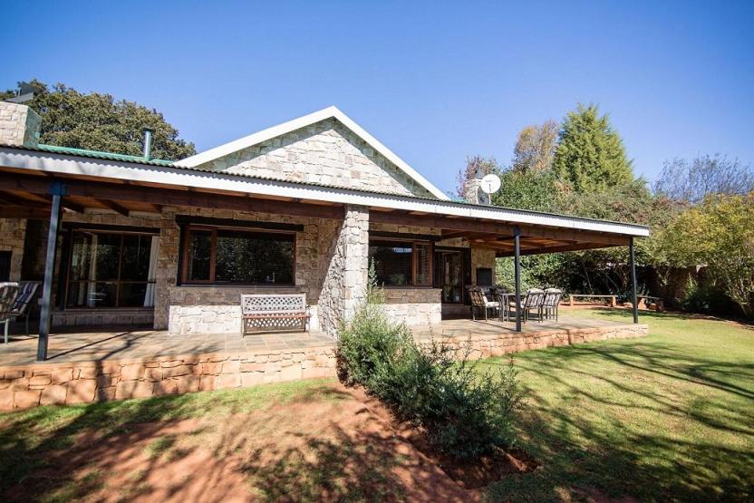 a stone house with a porch and a patio at Big Oak Cottages in Dullstroom