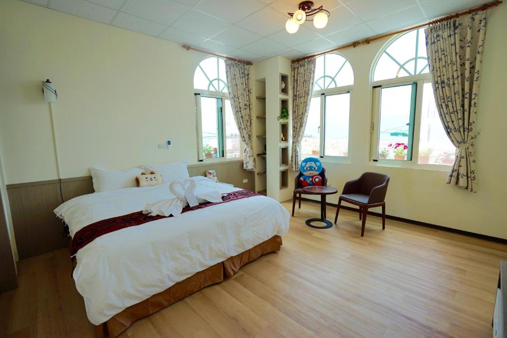 um quarto com uma cama, uma cadeira e janelas em David's House em Fanlu