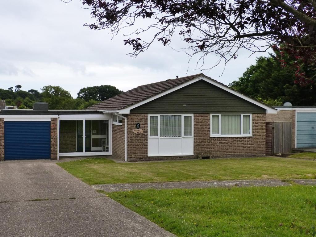 uma casa de tijolos com uma garagem azul em Solent View em Seaview