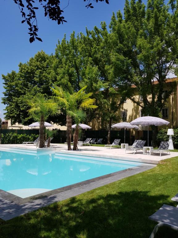 a swimming pool with lawn chairs and umbrellas at Hotel Hambros - Il Parco in Villa Banchieri in Lucca
