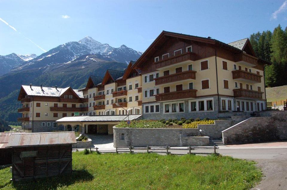 a large building with mountains in the background at Hotel Residence 3 Signori in Santa Caterina Valfurva