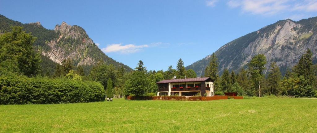 a house in a field with mountains in the background at Ferienwohnung 2 Gestüt Pfaffenlehen in Bischofswiesen