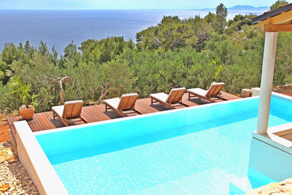 a pool with chairs and the ocean in the background at Villa Perka in Sveta Nedelja