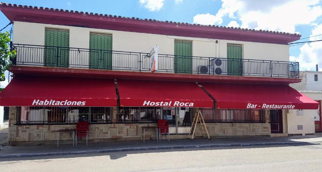 un restaurante con toldo rojo en un edificio en Hostal Roca, en Fayón