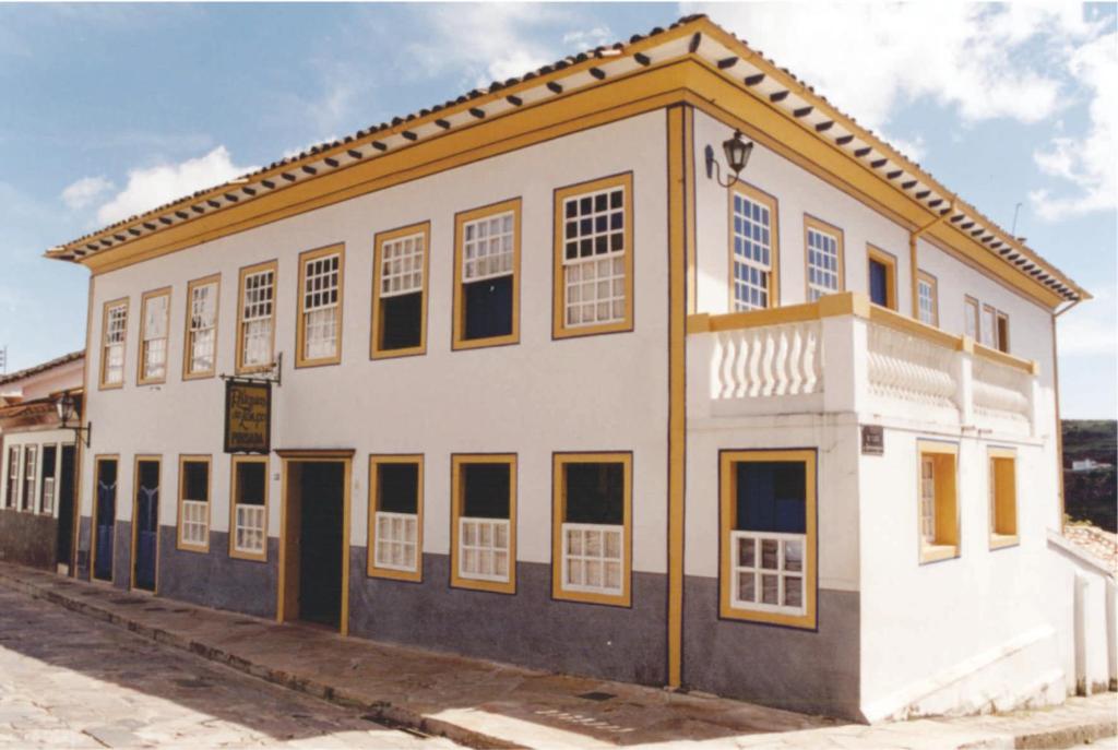 um antigo edifício branco com acentos amarelos em Pousada Relíquias do Tempo em Diamantina