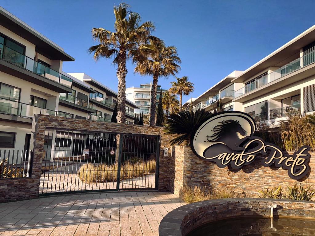 een poort bij de ingang van een hotel met palmbomen bij Cavalo Preto Luxury Beach Resort - C201 in Quarteira