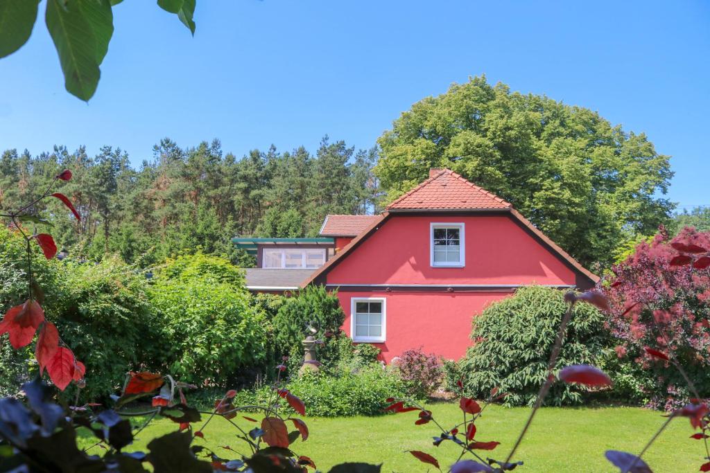 ein rotes Haus in einem Garten mit Bäumen in der Unterkunft Appartementhaus Sonnengarten in Silz