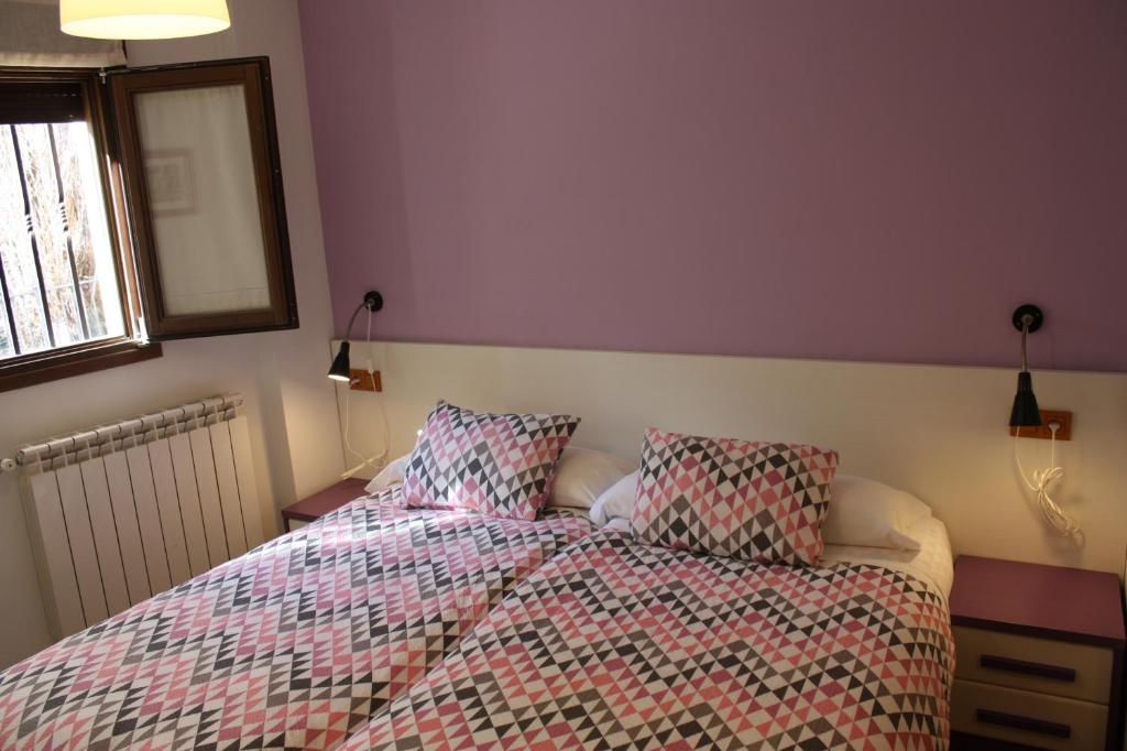 a bed with a comforter and pillows in a bedroom at Hostal La Ribera del Júcar in Cuenca
