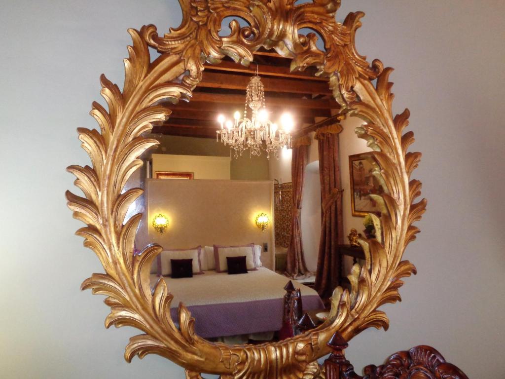 einen goldenen Spiegel mit einem Bett im Schlafzimmer in der Unterkunft Hotel Boutique Nueve Leyendas in Úbeda