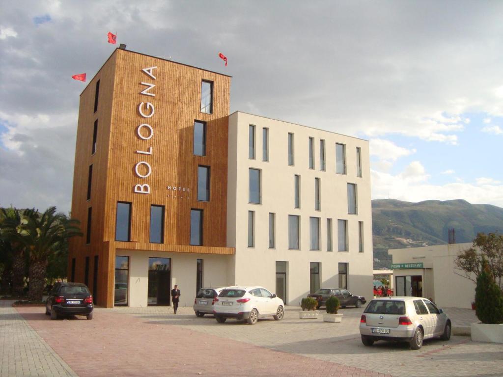 un bâtiment avec des voitures garées dans un parking dans l'établissement Hotel Bologna, à Vlorë