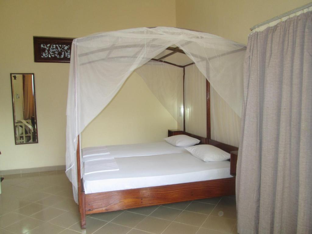 a bed with a canopy in a room at Tandem Guesthouse in Hikkaduwa