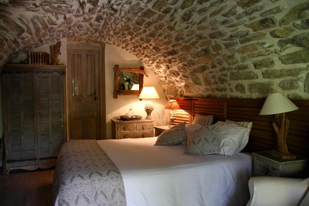 1 dormitorio con cama y pared de piedra en Mas de la Filoselle, en Saint-Martin-de-Valgalgues