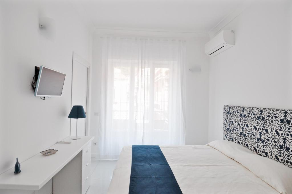 een witte slaapkamer met een bed en een bureau bij Iris Amalfi Dreams in Minori