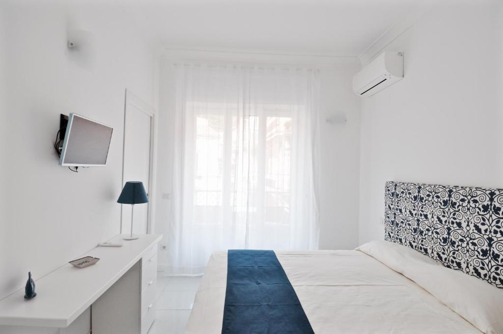 biała sypialnia z łóżkiem i biurkiem w obiekcie Iris Amalfi Dreams w mieście Minori