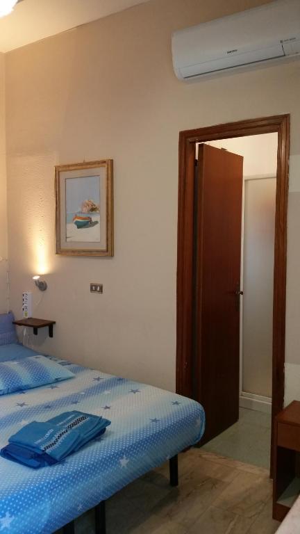 Schlafzimmer mit einem Bett mit blauer Decke in der Unterkunft Monolocale Seaside in Reggio di Calabria