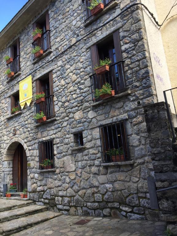 a stone building with windows and potted plants on it at Pensión Panticosa in Panticosa