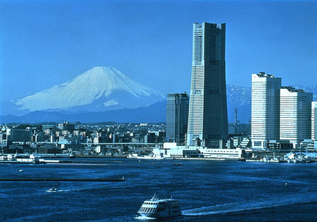 una città con una montagna sullo sfondo e una barca in acqua di Yokohama Royal Park Hotel a Yokohama