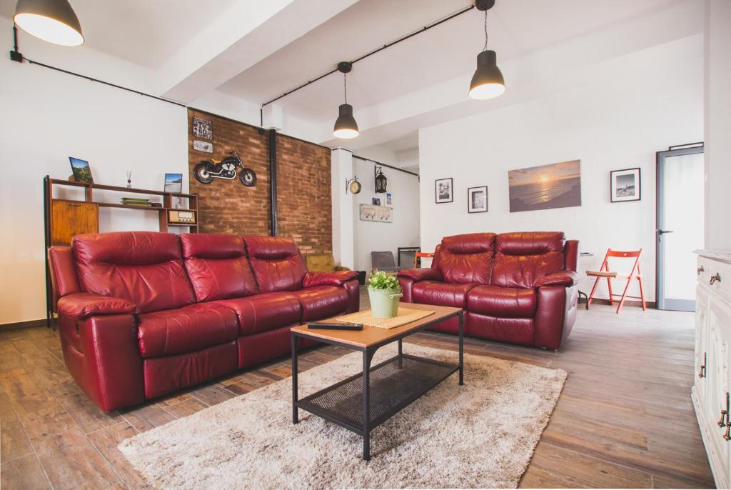 a living room with red leather couches and a table at Ardmar B&B in Vila do Bispo