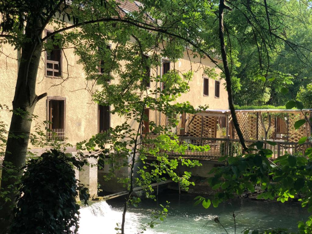 un bâtiment avec une rivière devant lui dans l'établissement La Residence du Moulin, à Sainte-Maure