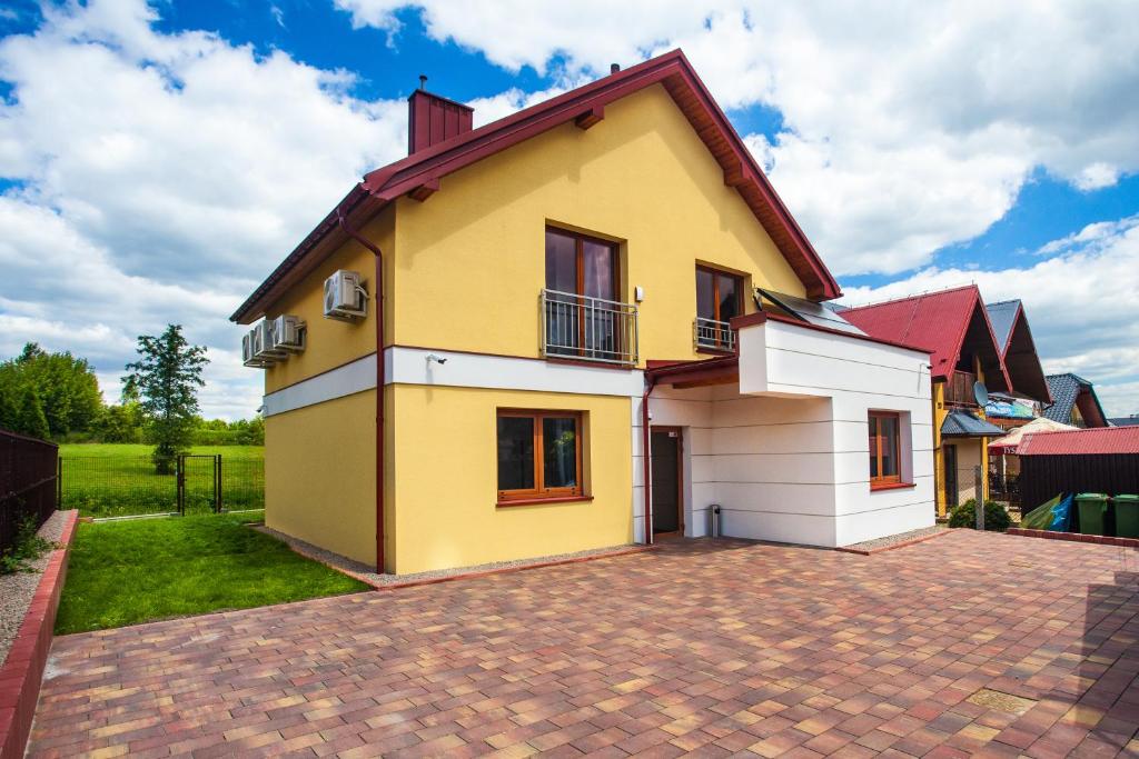 a yellow and white house with a brick driveway at Apartamenty SaltApart2 in Wieliczka