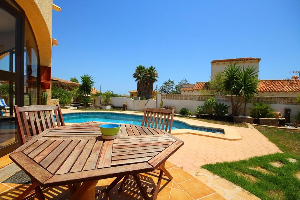 una mesa de madera y sillas junto a una piscina en Villa con piscina privada - Benicolada en Calpe