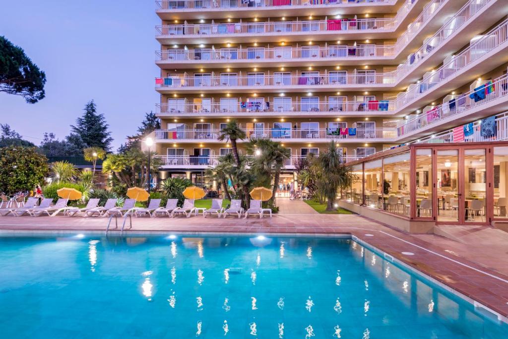 um hotel com piscina em frente a um edifício em Hotel President em Calella