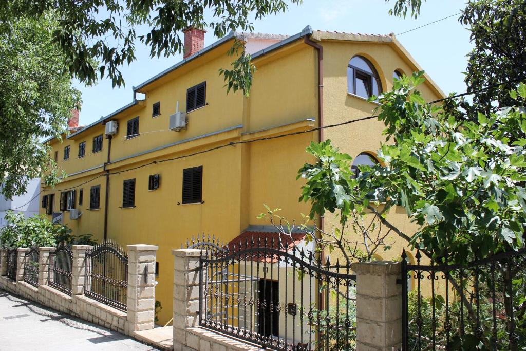 una casa amarilla con una valla delante de ella en Eros Rooms en Split
