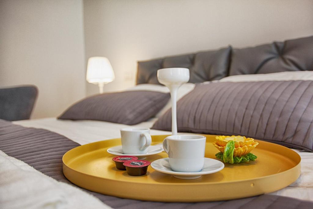 ein Tablett mit zwei Tassen und ein Tablett mit Essen auf einem Bett in der Unterkunft IMHOME - Fontana in Mailand