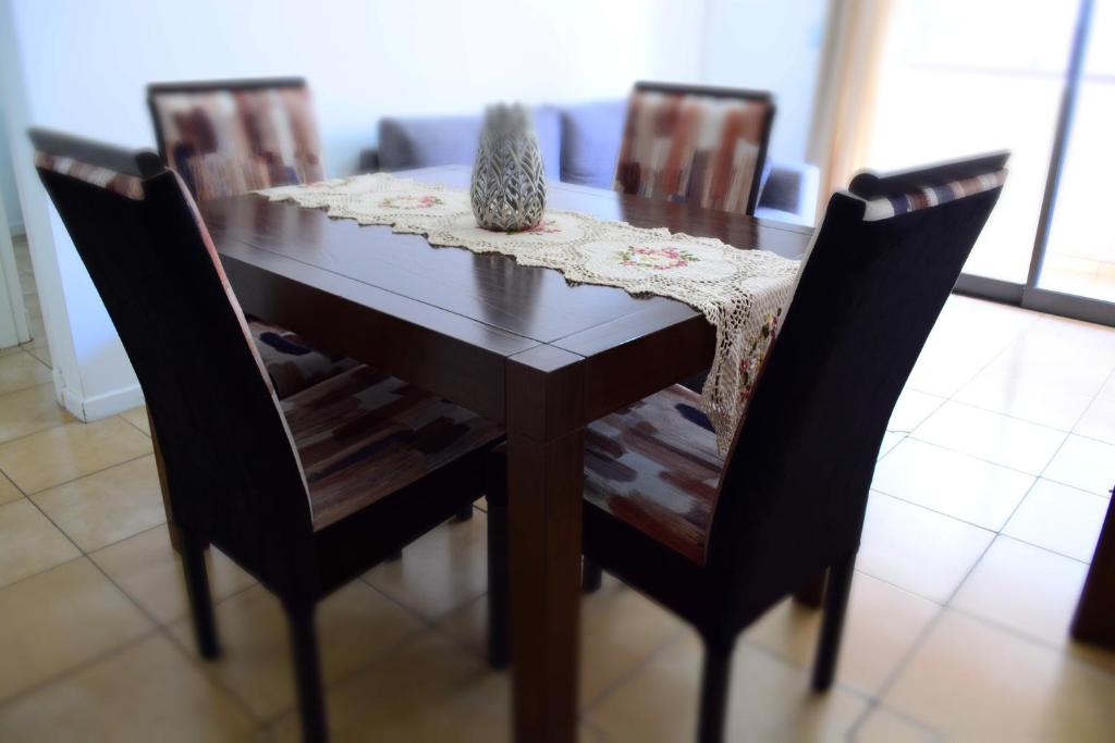 una mesa de madera con 4 sillas y un jarrón encima en Santorini 1 en Córdoba